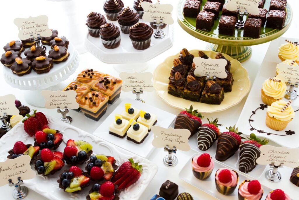 Vetrina di dolci e pasticcini mignon assortiti, etichettati con gusti come cioccolato, caramello, frutta e cheesecake.