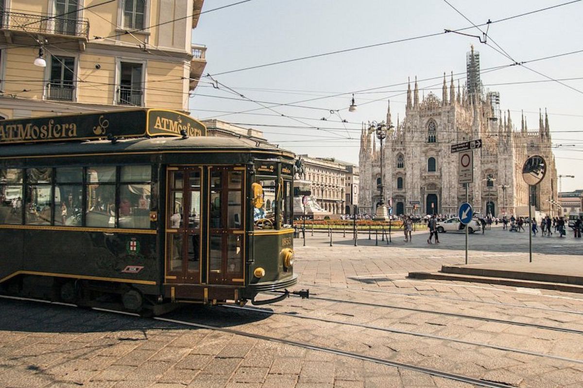 Tram ristorante storico "ATMosfera" a Milano, in una piazza assolata con il Duomo sullo sfondo.