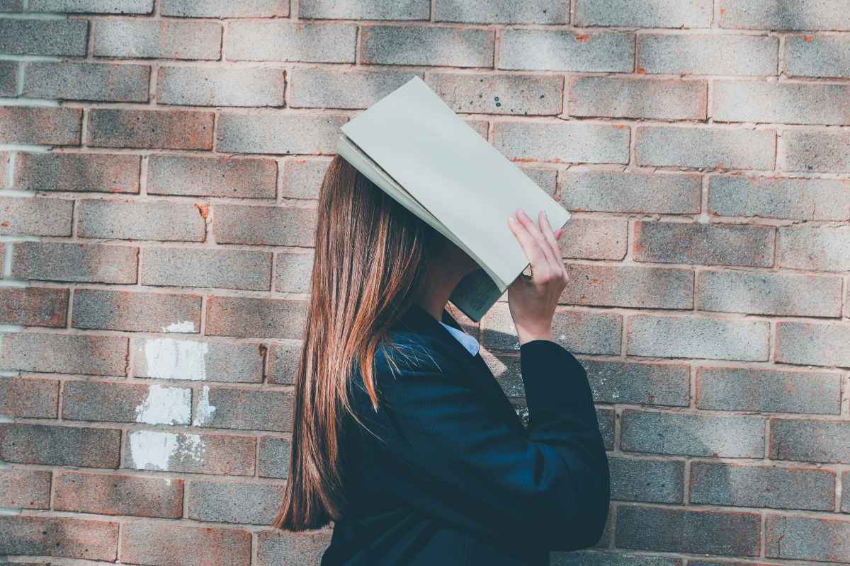 ragazzina con libro sul volto