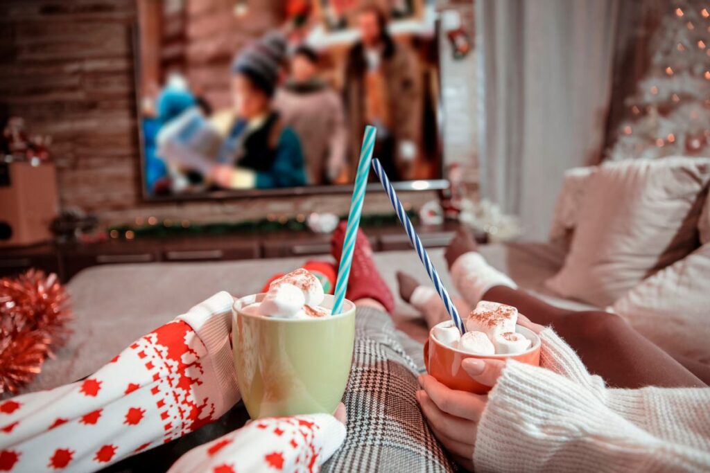 Due persone sul divano con cioccolata calda e marshmallow guardano un film su Netflix.