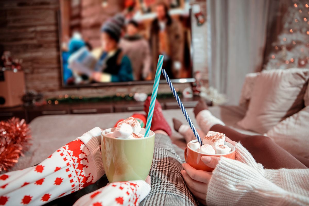 Due persone sul divano con cioccolata calda e marshmallow guardano un film su Netflix.