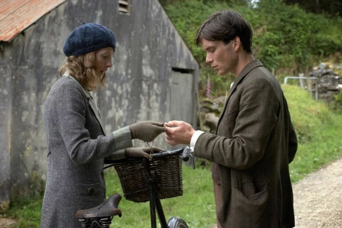 Scena del film “Il vento che accarezza l’erba” di Ken Loach, due giovani irlandesi si scambiano un oggetto davanti a una bicicletta.