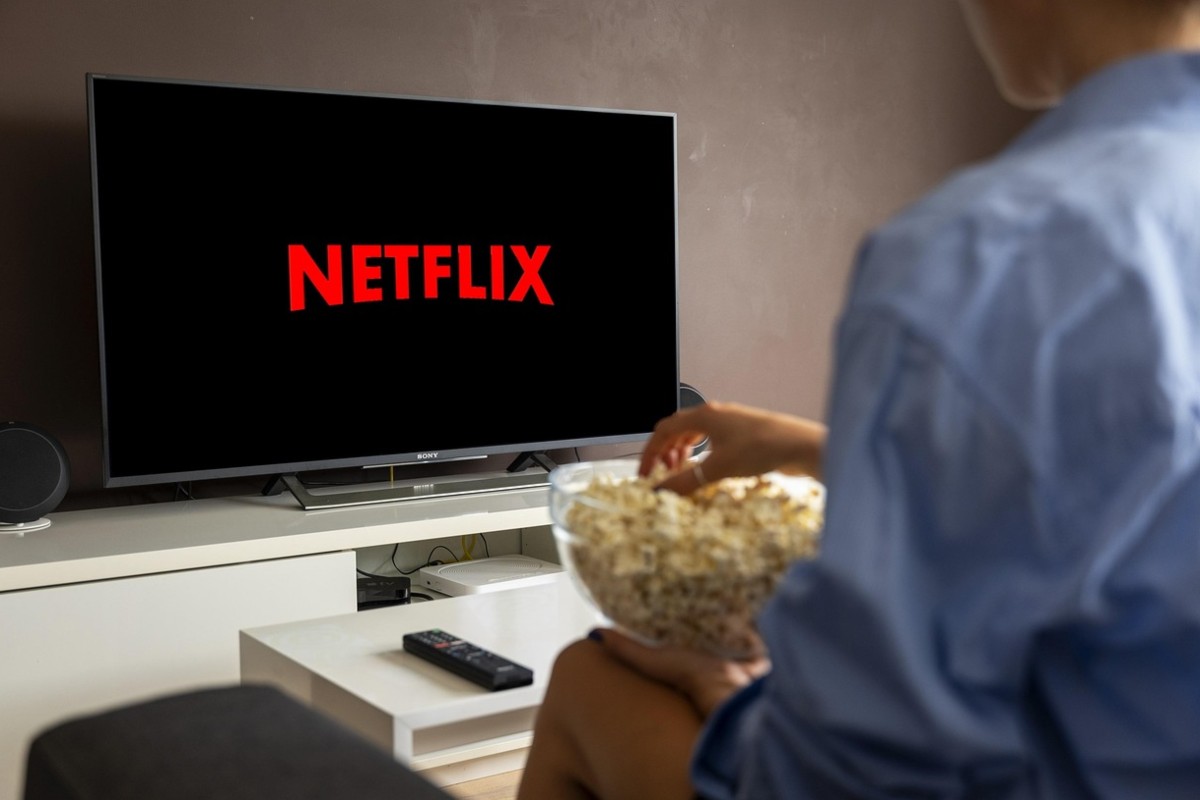 persona che guarda tv con ciotola di popcorn
