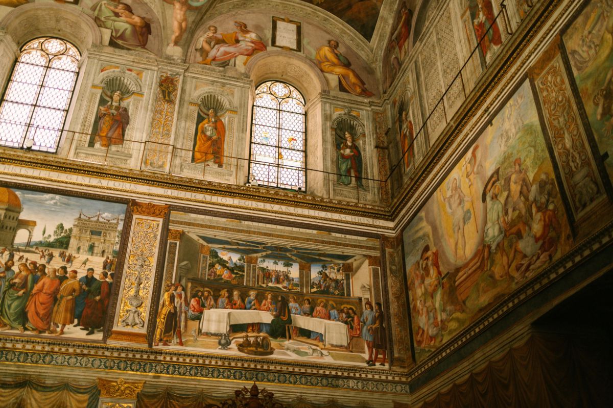 Affreschi storici in una cappella o sala d'arte, che mostrano figure e scene religiose, con due finestre in alto.